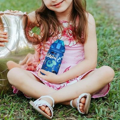 Fillette assise herbe gourde isotherme enfant en main