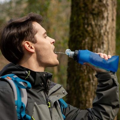 Homme boit bouteille filtrante pendant randonnée
