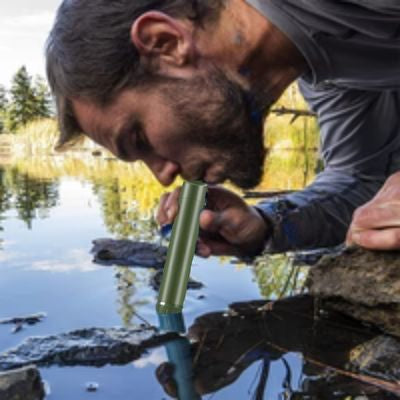 Homme boit dans étang directement avec filtre à eau