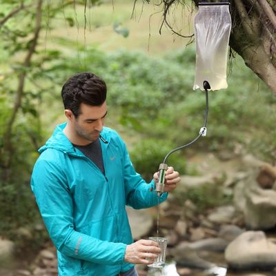 Homme manie filtre à eau par gravité attaché arbre