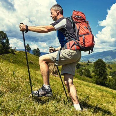 Homme monte colline avec batons pour marche nordique