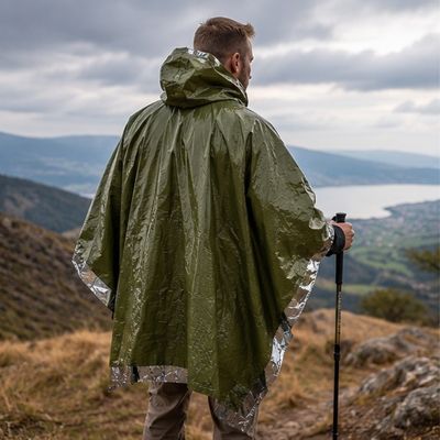 Homme randonne couvert poncho de survie sur crêtes