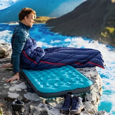 Homme réveil sac de couchage rocher surplomb rivière agitée