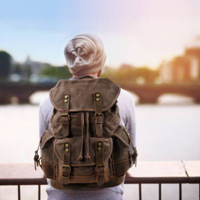 Sac à dos cuir homme observe rivière pont en ville